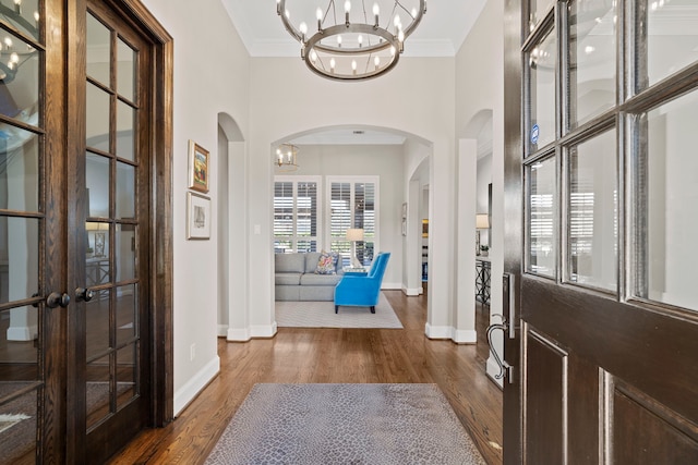 entryway with hardwood / wood-style floors, an inviting chandelier, ornamental molding, and french doors