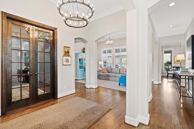 entrance foyer featuring french doors, an inviting chandelier, ornamental molding, and wood-type flooring