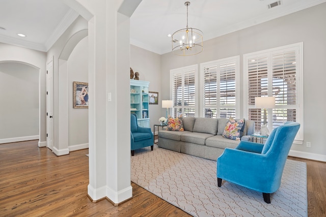 living room featuring wood-type flooring, ornamental molding, and a notable chandelier