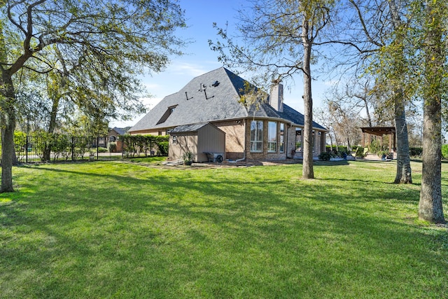 rear view of house featuring a lawn and a storage unit