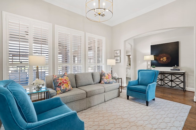 living room featuring an inviting chandelier, wood-type flooring, plenty of natural light, and crown molding