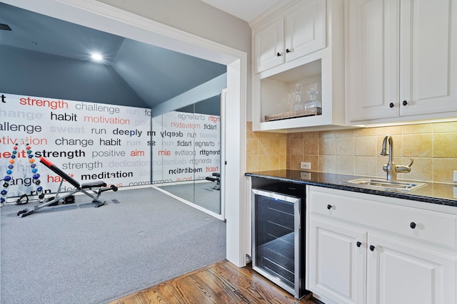 kitchen featuring dark hardwood / wood-style floors, beverage cooler, white cabinets, and sink