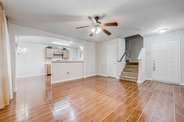 unfurnished living room featuring ceiling fan with notable chandelier