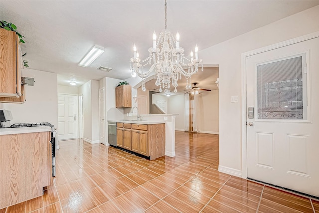 kitchen with kitchen peninsula, stainless steel appliances, pendant lighting, ceiling fan with notable chandelier, and sink