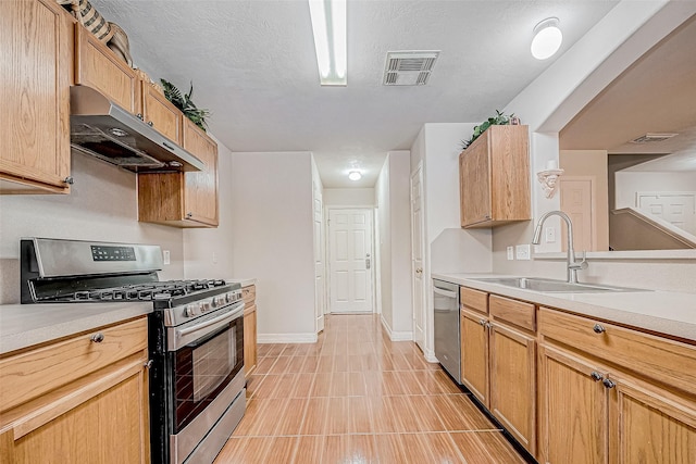 kitchen featuring a textured ceiling, stainless steel appliances, and sink