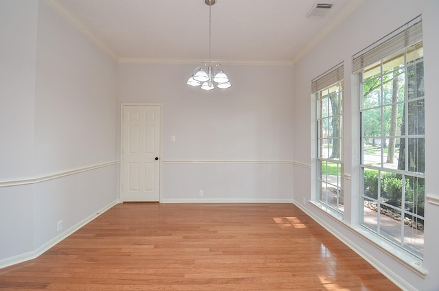 spare room featuring a chandelier, crown molding, and light hardwood / wood-style flooring