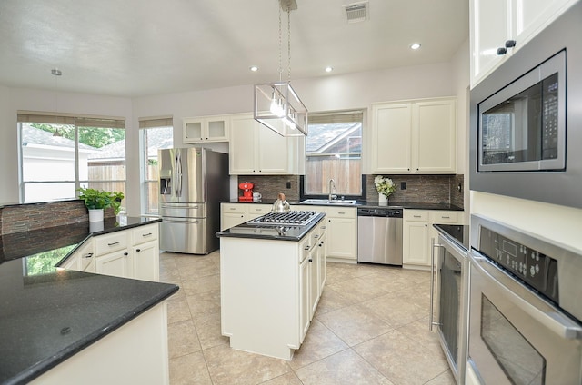 kitchen featuring white cabinets, a center island, stainless steel appliances, and pendant lighting