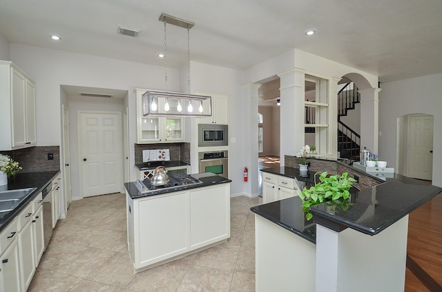 kitchen featuring decorative light fixtures, backsplash, a center island, appliances with stainless steel finishes, and white cabinets