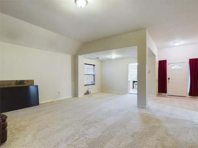 unfurnished living room featuring light colored carpet and vaulted ceiling