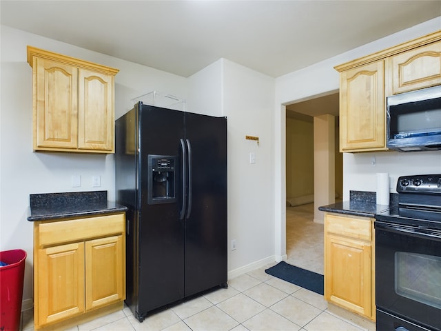 kitchen featuring light brown cabinetry, light tile patterned floors, black appliances, and dark stone countertops