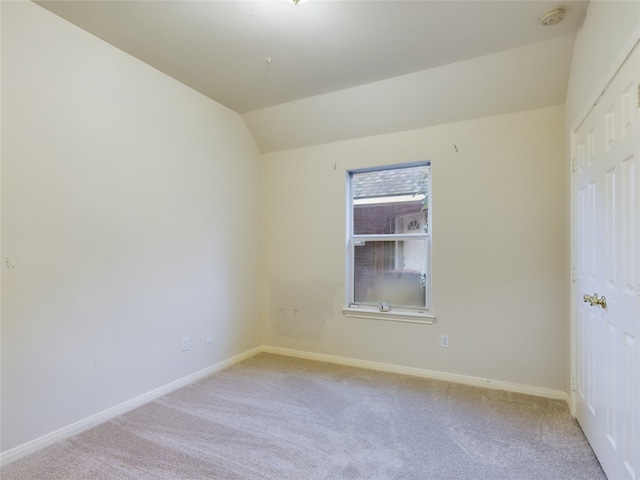 spare room featuring light colored carpet and lofted ceiling