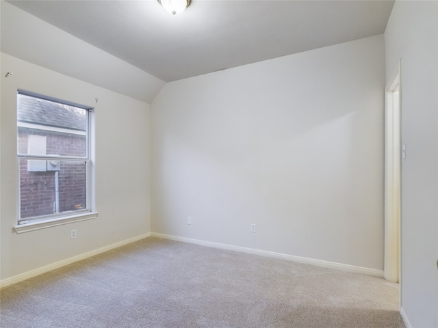 carpeted empty room with lofted ceiling