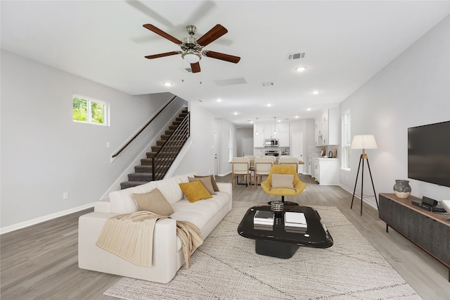 living room with ceiling fan and light hardwood / wood-style flooring