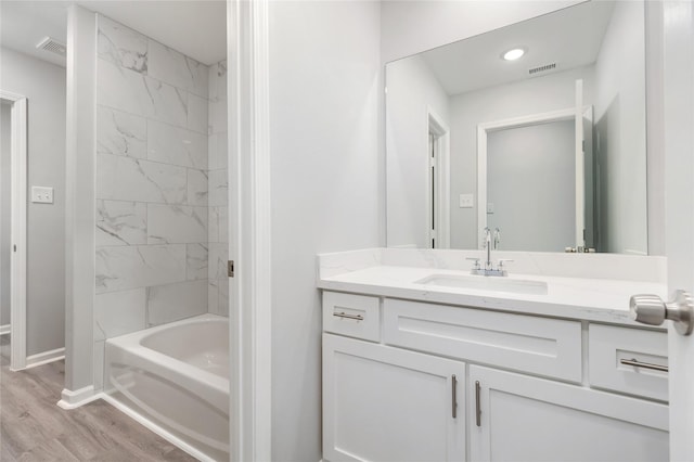 bathroom featuring hardwood / wood-style floors, tiled shower / bath combo, and vanity