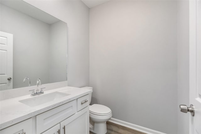 bathroom with toilet, vanity, and hardwood / wood-style floors