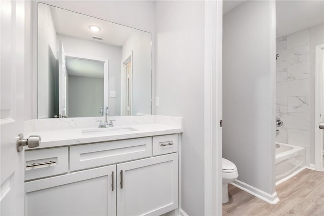 full bathroom with toilet, vanity, tiled shower / bath, and hardwood / wood-style floors