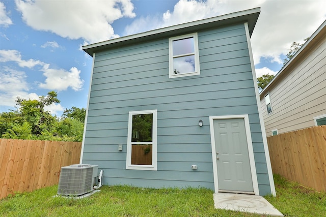 rear view of property featuring central AC unit and a yard