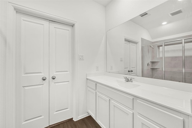 bathroom with vanity, vaulted ceiling, a shower with door, and hardwood / wood-style floors