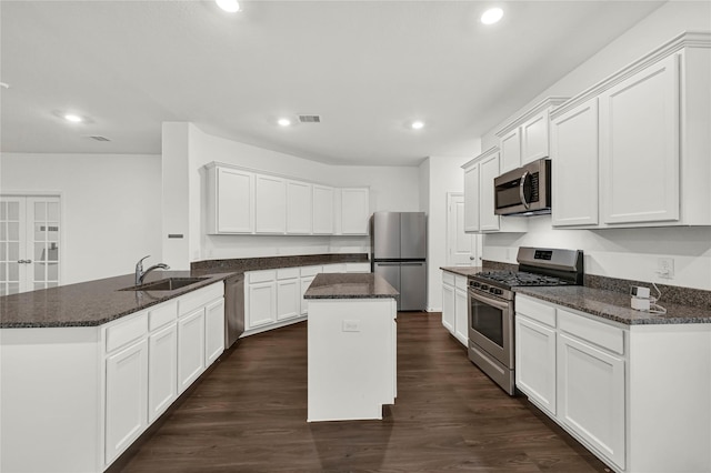 kitchen with white cabinetry, a center island, stainless steel appliances, and dark stone countertops