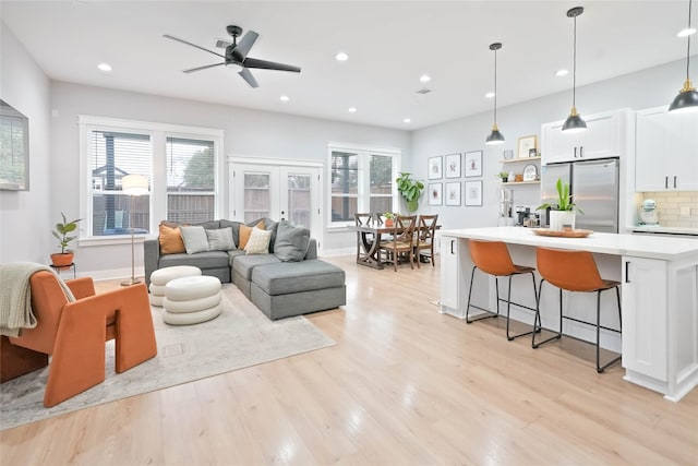 living room with ceiling fan, light hardwood / wood-style floors, and french doors