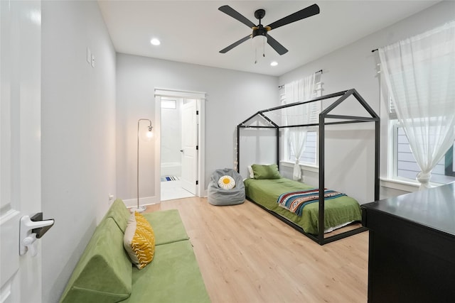 bedroom with ceiling fan, connected bathroom, and hardwood / wood-style floors