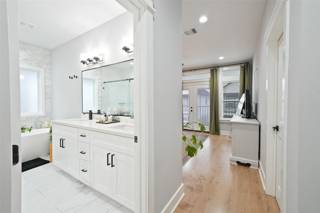 bathroom with a wealth of natural light, a tub to relax in, hardwood / wood-style flooring, and vanity