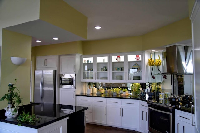 kitchen featuring appliances with stainless steel finishes, exhaust hood, white cabinets, and decorative backsplash