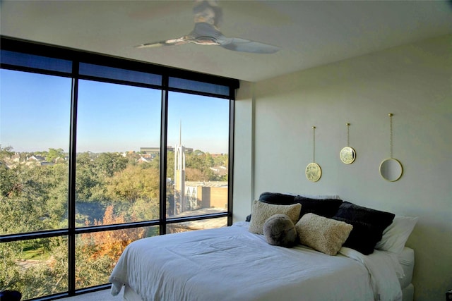 bedroom featuring ceiling fan and a wall of windows