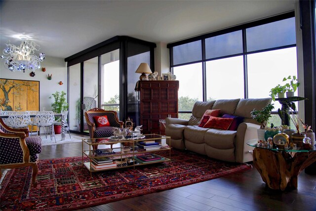 living room with a wall of windows, a notable chandelier, a wealth of natural light, and hardwood / wood-style flooring