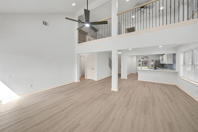 unfurnished living room featuring high vaulted ceiling, light hardwood / wood-style floors, and ceiling fan