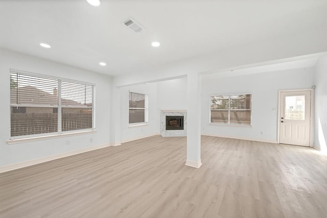 unfurnished living room featuring a premium fireplace and light hardwood / wood-style flooring