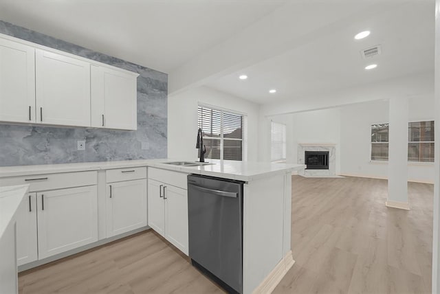 kitchen featuring white cabinetry, kitchen peninsula, dishwasher, a high end fireplace, and sink