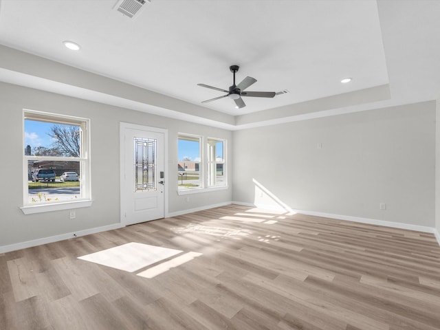 spare room with ceiling fan, light hardwood / wood-style floors, and a raised ceiling