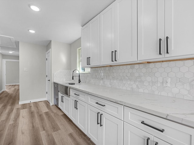 kitchen with white cabinetry, light hardwood / wood-style floors, and light stone countertops