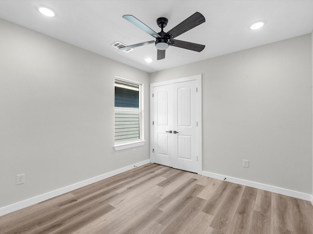 unfurnished bedroom featuring ceiling fan, a closet, and light wood-type flooring