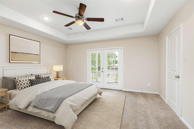 carpeted bedroom with ceiling fan, access to exterior, french doors, and a tray ceiling