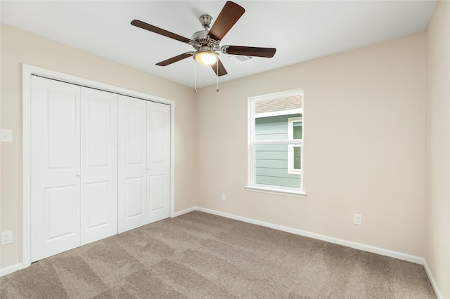 unfurnished bedroom featuring ceiling fan, light colored carpet, and a closet