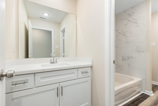 bathroom featuring tiled shower / bath, wood-type flooring, and vanity