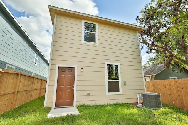 rear view of property featuring central AC unit and a yard