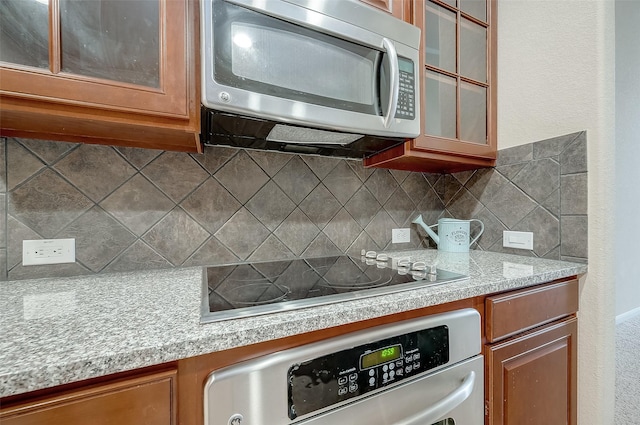 kitchen featuring stainless steel appliances, tasteful backsplash, and light stone counters