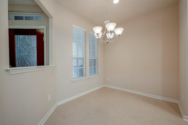 tiled spare room with a notable chandelier