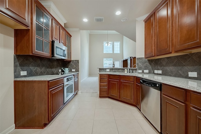 kitchen with light stone countertops, decorative light fixtures, stainless steel appliances, decorative backsplash, and ceiling fan