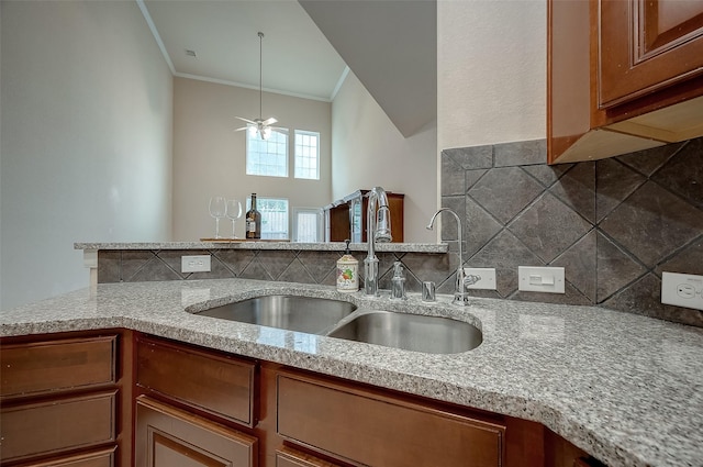 kitchen featuring ceiling fan, light stone countertops, sink, and ornamental molding