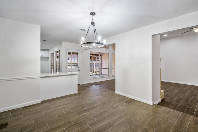 interior space with ceiling fan with notable chandelier, hanging light fixtures, white cabinetry, and a textured ceiling