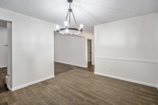 empty room featuring a textured ceiling and a notable chandelier