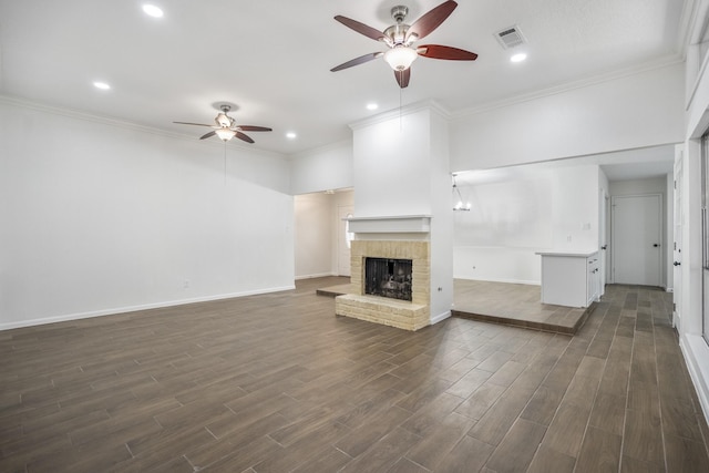 unfurnished living room with a brick fireplace, crown molding, and ceiling fan with notable chandelier