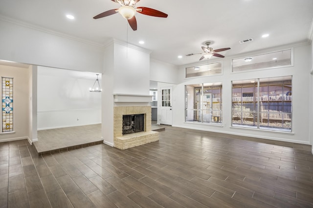 unfurnished living room with a brick fireplace, ornamental molding, and ceiling fan with notable chandelier