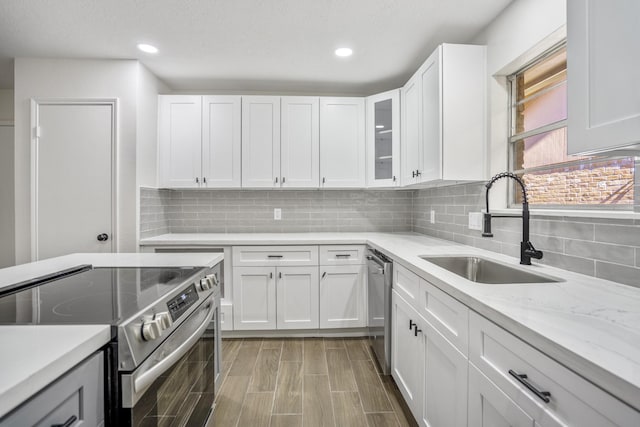 kitchen featuring light stone counters, sink, white cabinetry, and appliances with stainless steel finishes