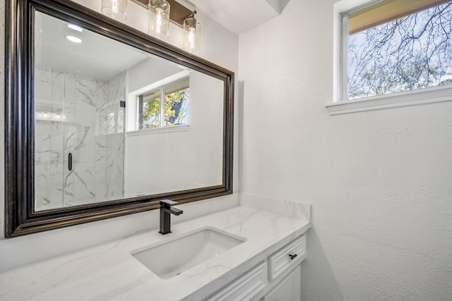 bathroom featuring a shower with shower door and vanity