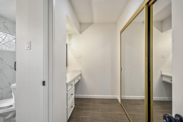 bathroom featuring toilet, a tile shower, and vanity